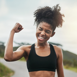 Strong mom celebrating after an outdoor workout by holding up one arm.